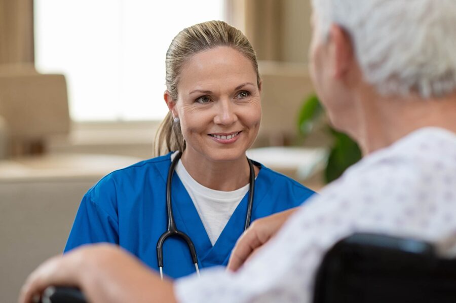 Caring nurse smiling at an elderly patient.