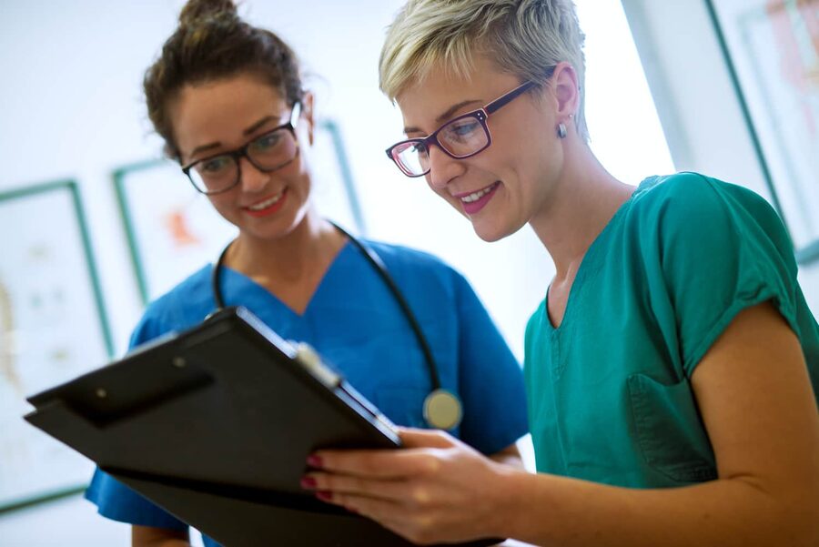 Two nurses reviewing patient notes together, representing collaboration and professional.